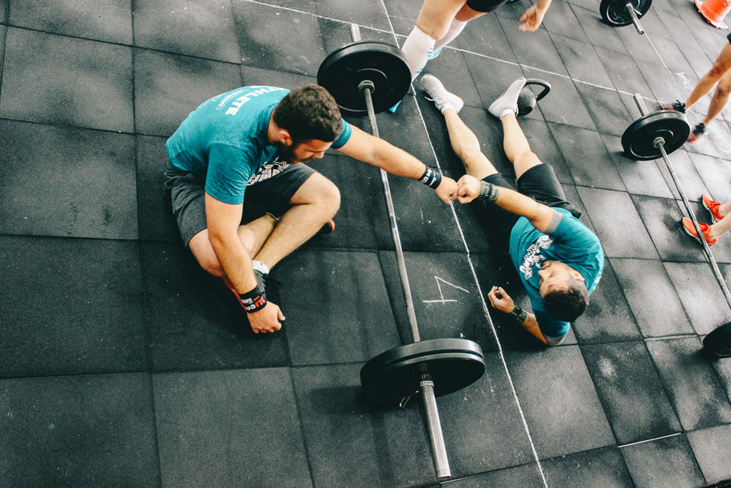 Two guys fist bump on the floor after a workout